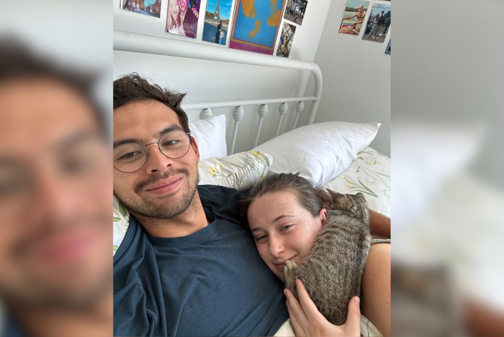 couple laying in bed with their cat