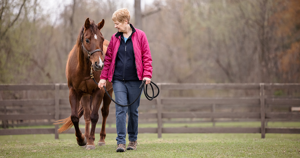 a woman in a pink jacket with a horse