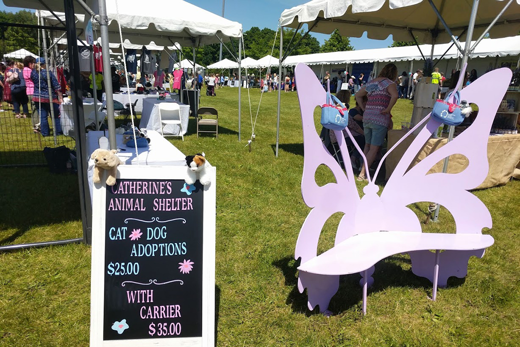 A sign for the event next to a lavender butterfly bench