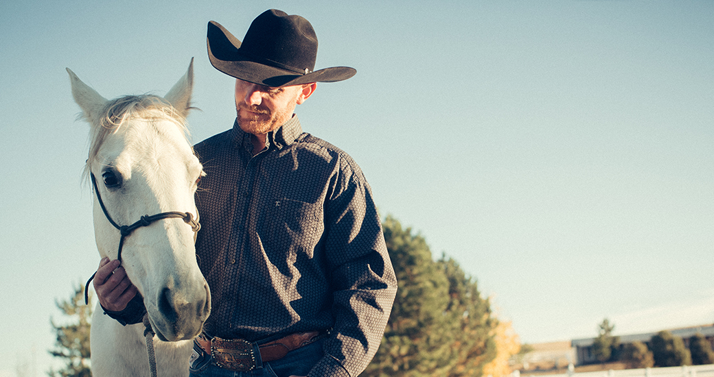 a man wearing a cowboy hat with a white horse