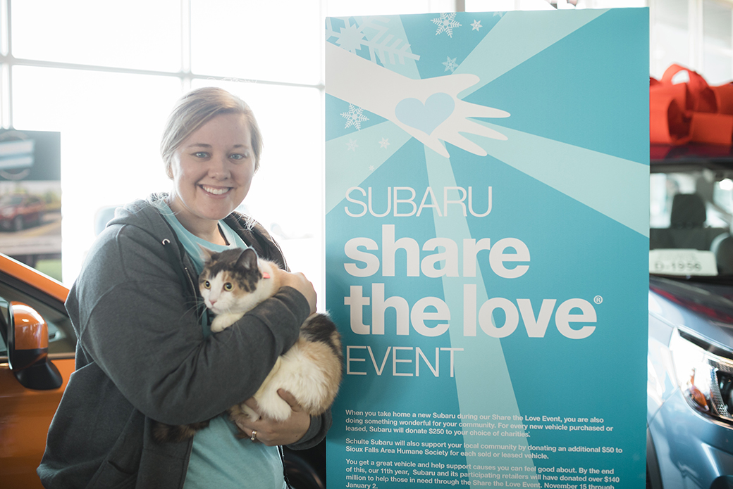 a woman holding a cat near a share the love sign