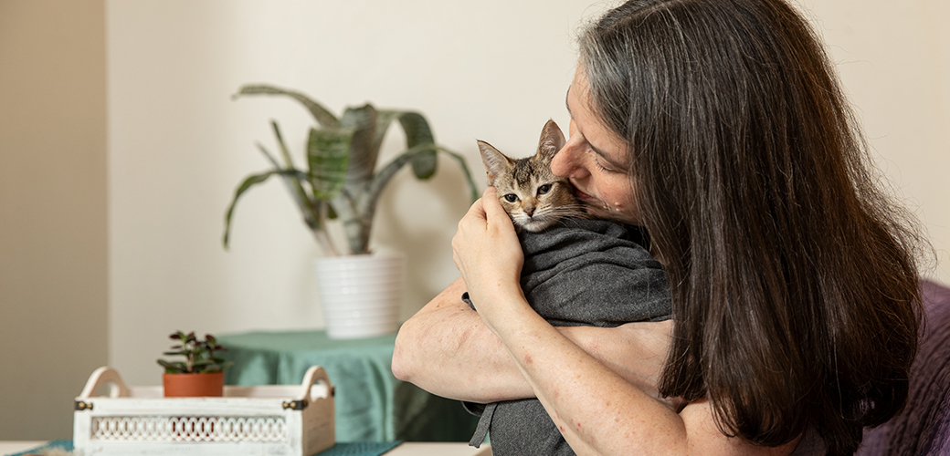 a woman hugging a cat wrapped in a blanket