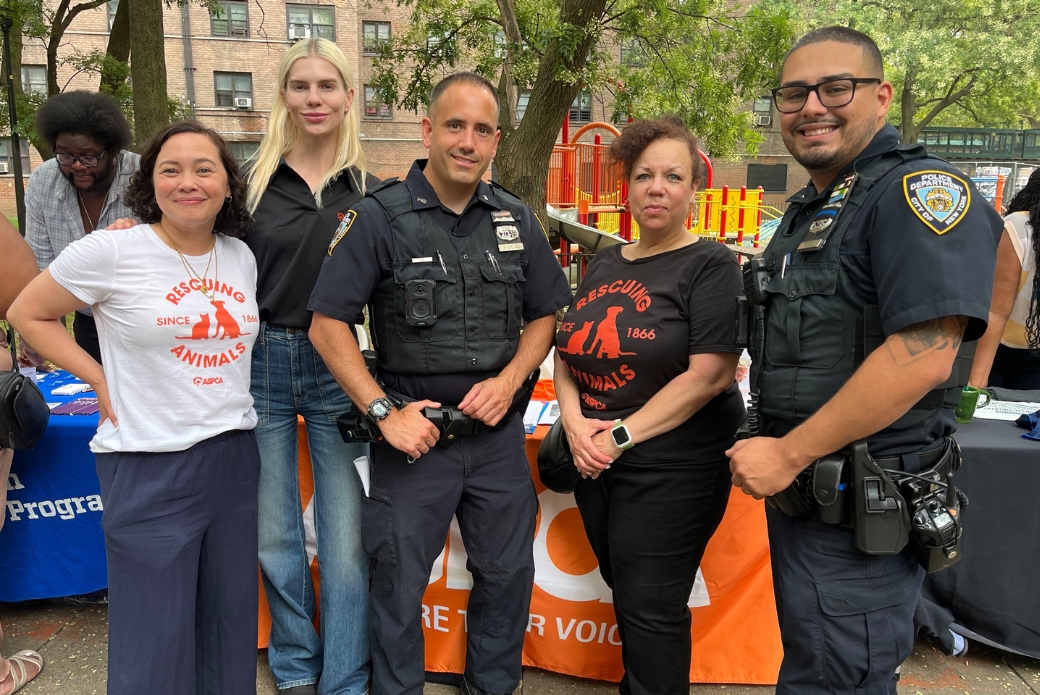 ASPCA staff and NYPD officers posing in front of an event booth