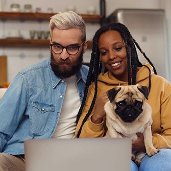 a young couple with a pug looking at a computer